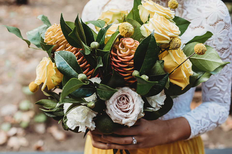  groom in an ivory paisley tuxedo and gold velvet bow tie and the bride in a two-piece gown with a yellow skirt and ivory long sleeve top 