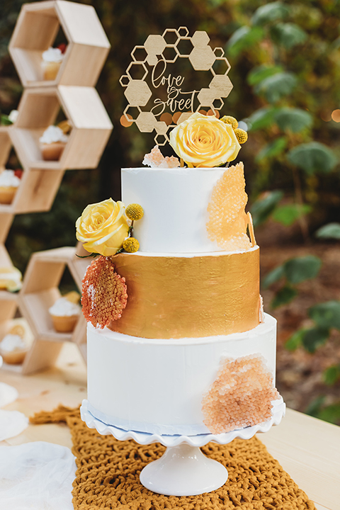  groom in an ivory paisley tuxedo and gold velvet bow tie and the bride in a two-piece gown with a yellow skirt and ivory long sleeve top 