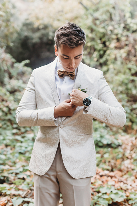  groom in an ivory paisley tuxedo and gold velvet bow tie and the bride in a two-piece gown with a yellow skirt and ivory long sleeve top 