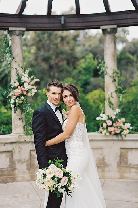  bride in a modern gown with a strapless neckline and the groom in a black tuxedo and bow tie 