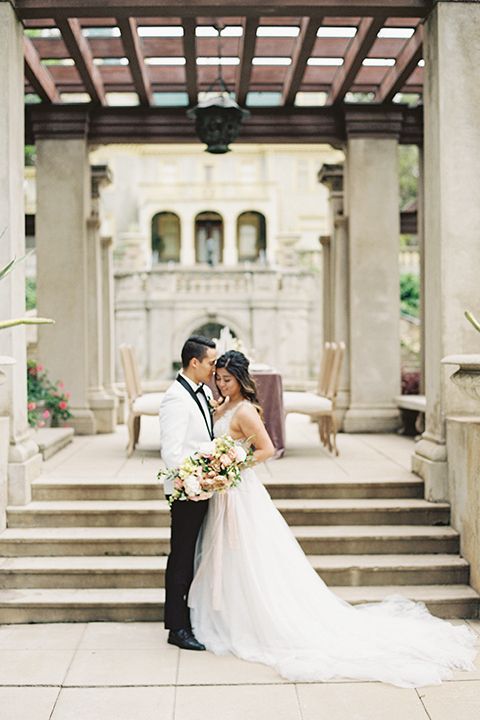  bride in a modern gown with a strapless neckline and the groom in a white tuxedo and bow tie 