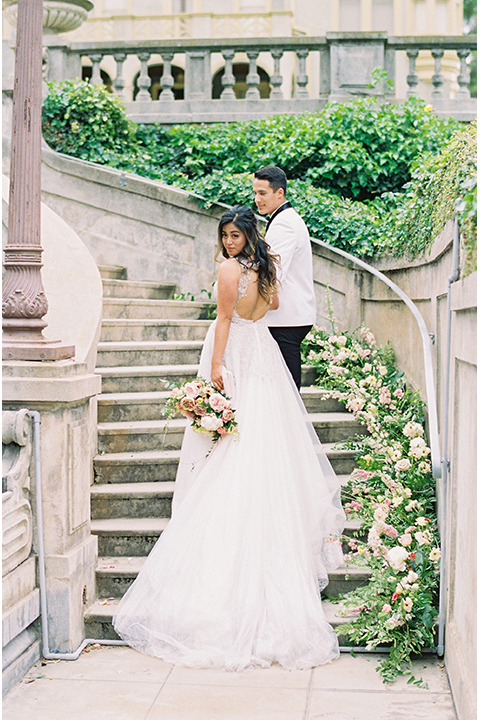  bride in a modern gown with a strapless neckline and the groom in a white tuxedo and bow tie 