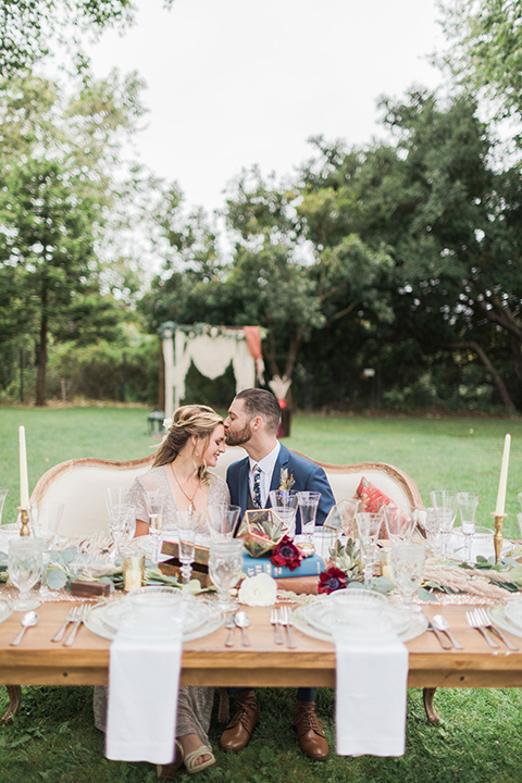  bride in an ivory and champagne gown with sleeves and the groom in a blue suit with a blue floral neck tie 