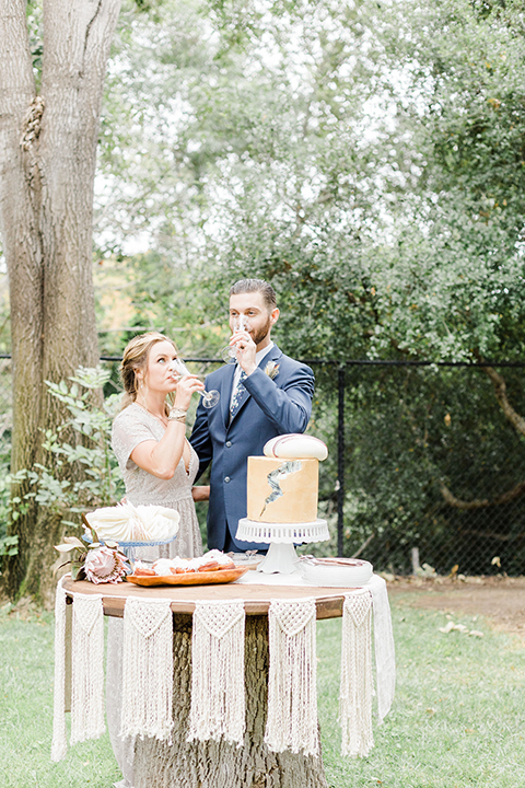  bride in an ivory and champagne gown with sleeves and the groom in a blue suit with a blue floral neck tie 