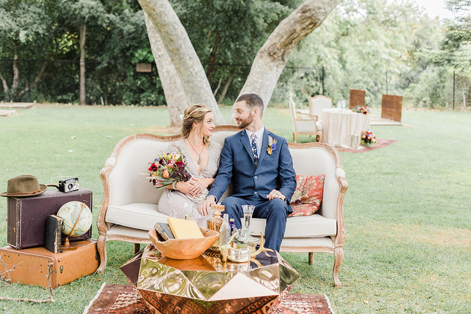  bride in an ivory and champagne gown with sleeves and the groom in a blue suit with a blue floral neck tie 