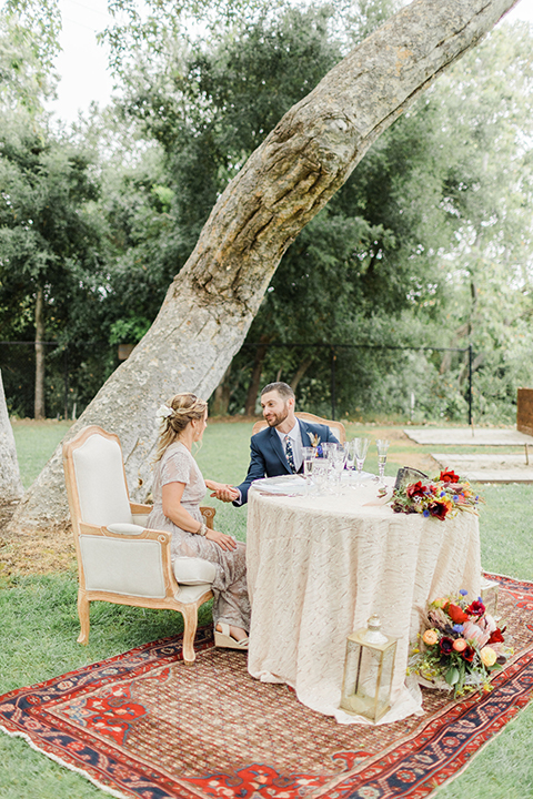  bride in an ivory and champagne gown with sleeves and the groom in a blue suit with a blue floral neck tie 