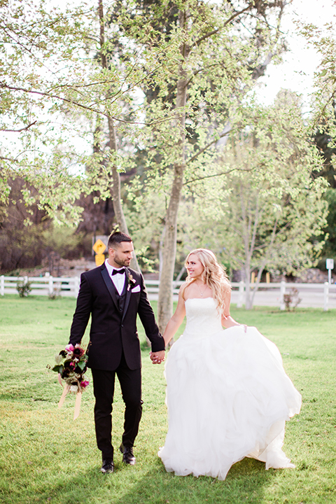  bride in a strapless white ball gown and the groom in a black tuxedo with black bowtie 