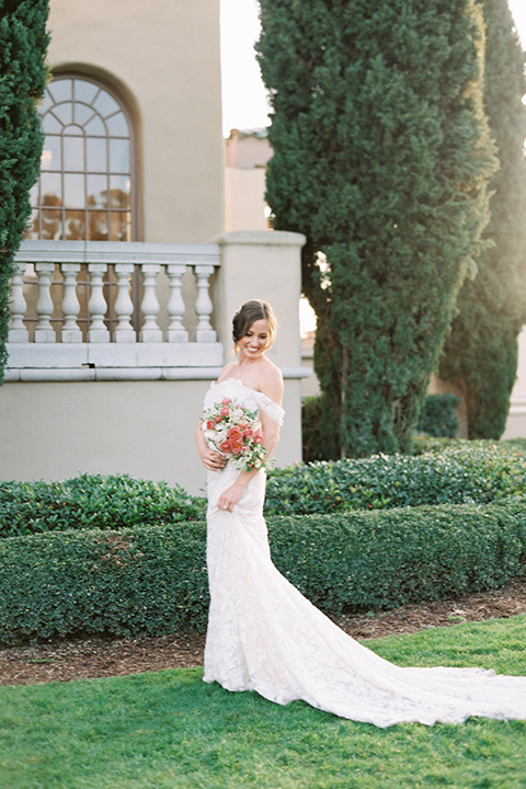  bride in a formfitting white lace gown with an off the shoulder detail 