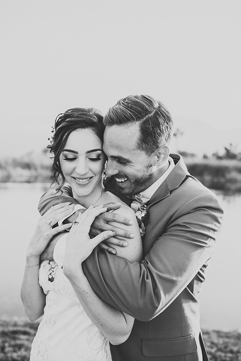  bride in a flowing lace gown and the groom in a rose pink suit