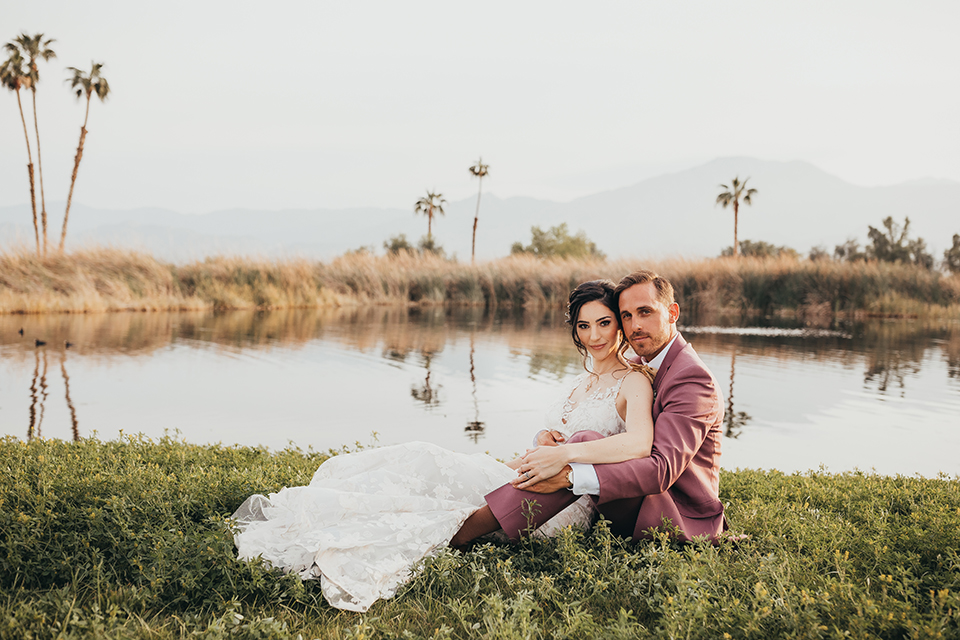  bride in a flowing lace gown and the groom in a rose pink suit 