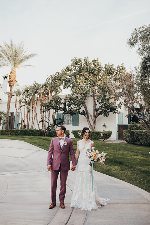  bride in a flowing lace gown and the groom in a rose pink suit 