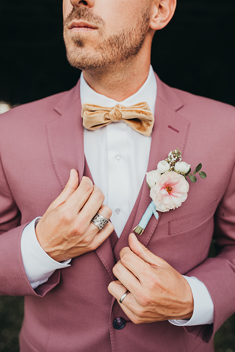  bride in a flowing lace gown and the groom in a rose pink suit 