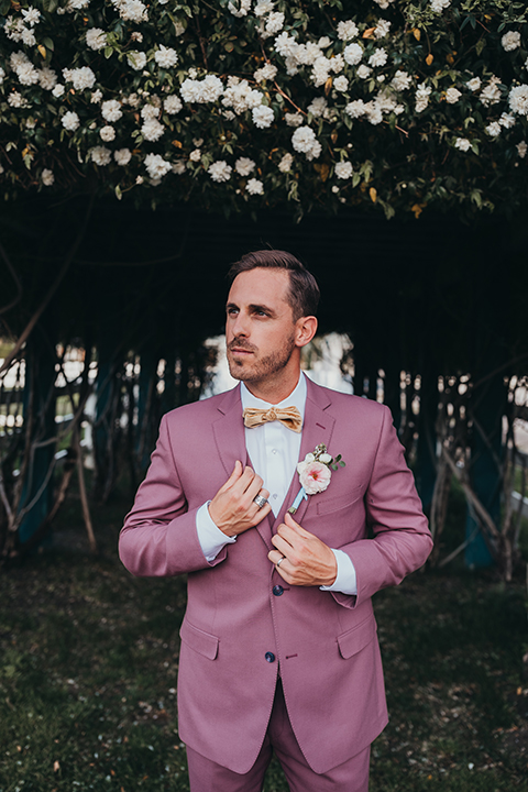  bride in a flowing lace gown and the groom in a rose pink suit