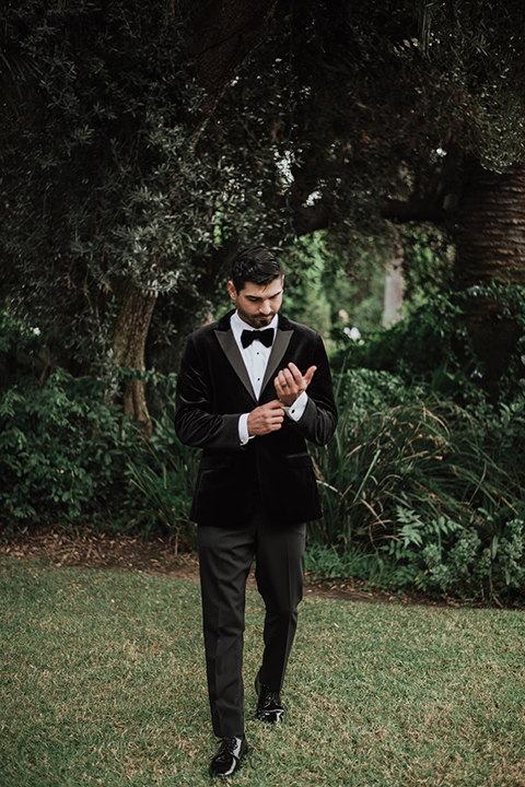  bride in a black gown with a black veil and the groom in a burgundy tuxedo with a black shirt and bow tie 