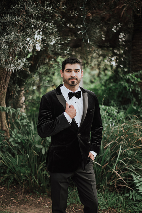  bride in a black gown with a black veil and the groom in a burgundy tuxedo with a black shirt and bow tie 