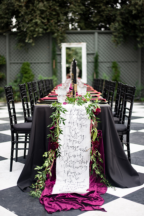  bride in a black gown with a black veil and the groom in a burgundy tuxedo with a black shirt and bow tie 