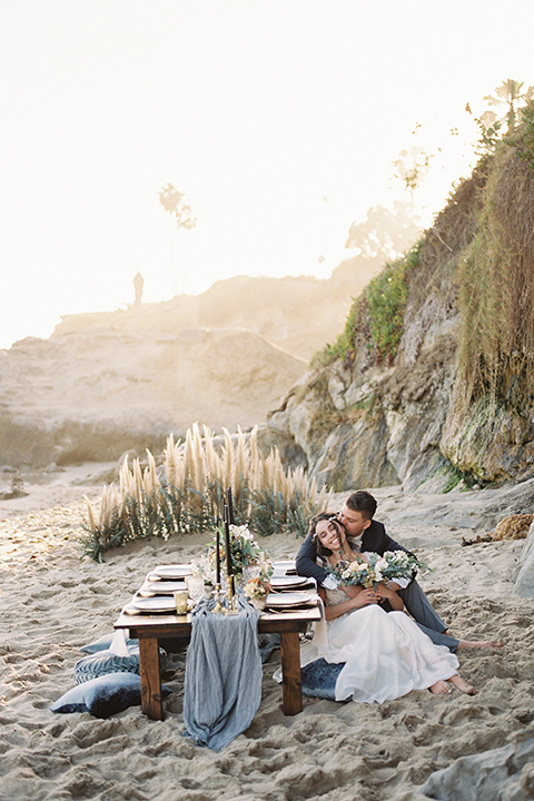  bride in  flowing gown with embellishments and the groom in a dark grey coat with light grey pants