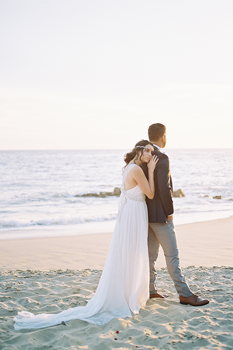  bride in  flowing gown with embellishments and the groom in a dark grey coat with light grey pants