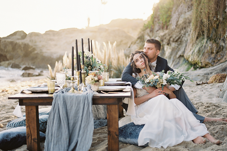  bride in  flowing gown with embellishments and the groom in a dark grey coat with light grey pants 