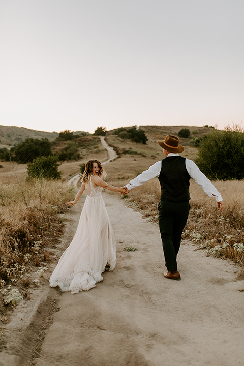  bride in a long white gown with a long train and boho hat