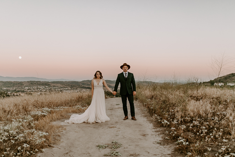  bride in a long white gown with a long train and boho hat 