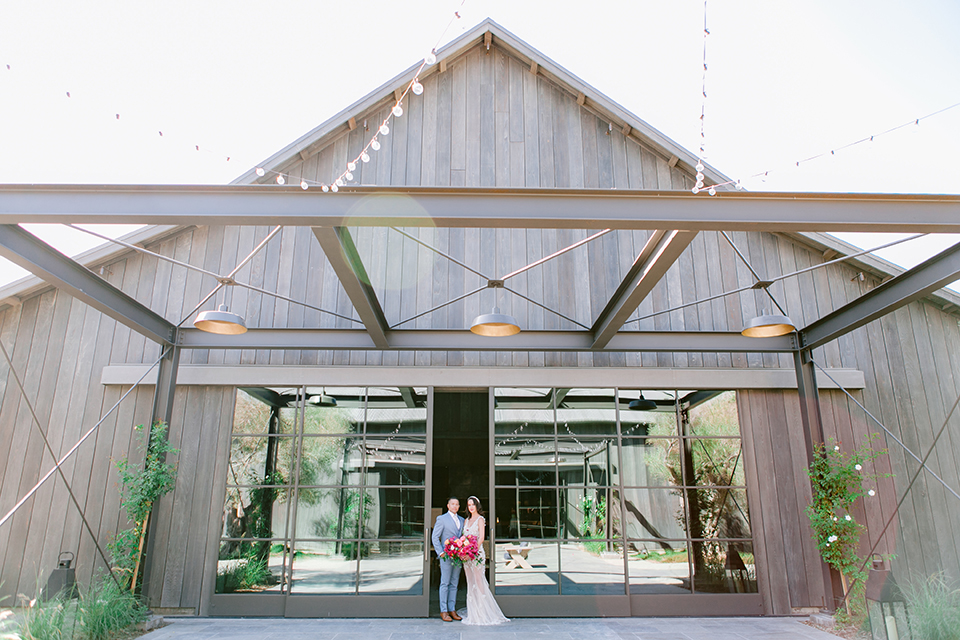  the bride in a lace gown and jean jacket and the groom in a light blue suit with a white floral long tie 