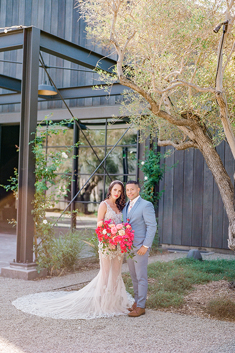  the bride in a lace gown and jean jacket and the groom in a light blue suit with a white floral long tie 