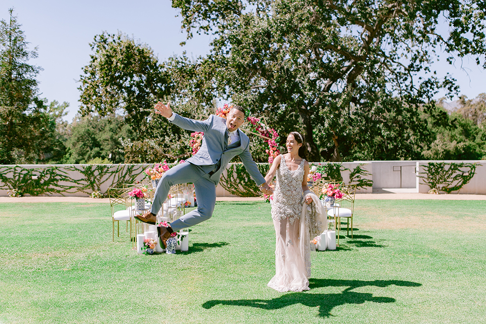  the bride in a lace gown and jean jacket and the groom in a light blue suit with a white floral long tie 