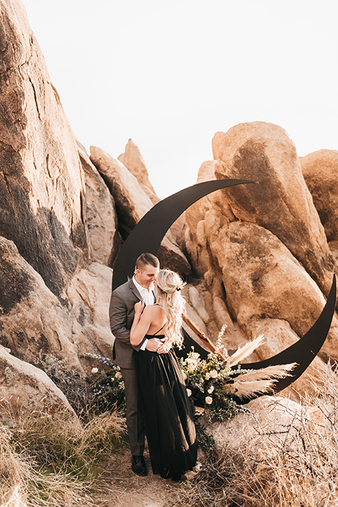  bride in a black gown and the groom in a café brown suit