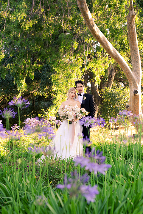  bride in a white flowing gown with a full skirt and the groom in a black tuxedo  