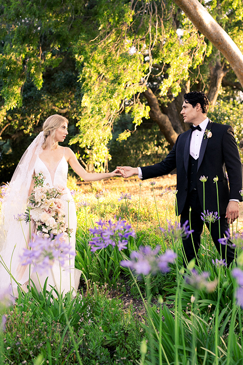  bride in a white flowing gown with a full skirt and the groom in a black tuxedo  