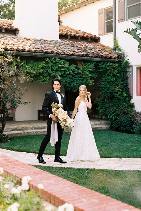  bride in a white flowing gown with a full skirt and the groom in a black tuxedo  