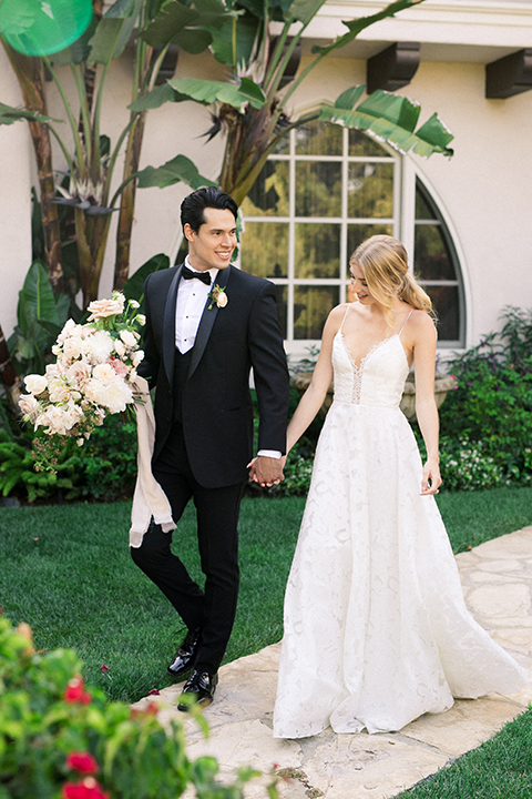  bride in a white flowing gown with a full skirt and the groom in a black tuxedo  