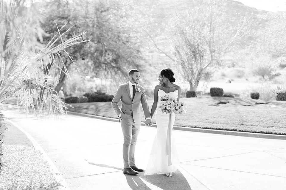  red rocks caramel wedding couple sitting – bride in a strapless modern gown and the groom in a caramel tan suit with a chocolate brown tie 