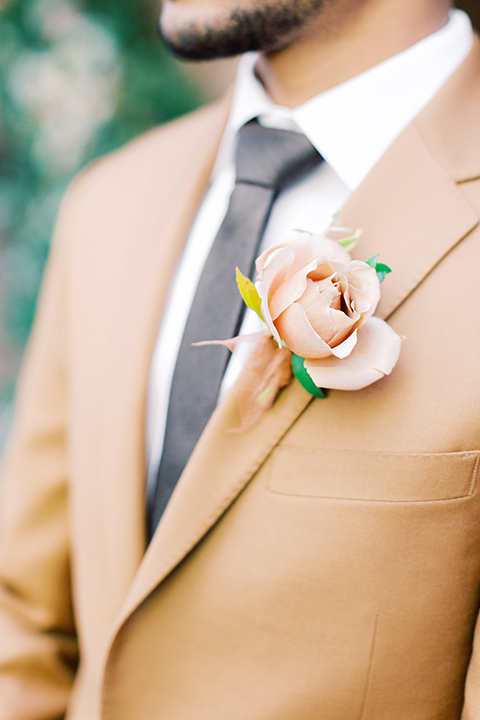  red rocks caramel wedding couple sitting – bride in a strapless modern gown and the groom in a caramel tan suit with a chocolate brown tie