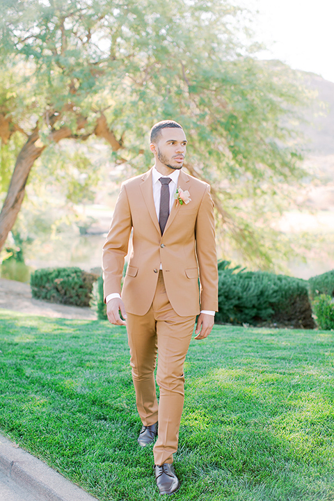  red rocks caramel wedding couple sitting – bride in a strapless modern gown and the groom in a caramel tan suit with a chocolate brown tie 