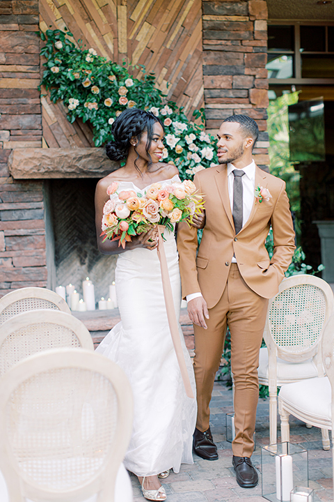  red rocks caramel wedding couple sitting – bride in a strapless modern gown and the groom in a caramel tan suit with a chocolate brown tie 