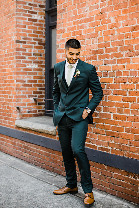  bride in an ivory lace gown with modern style design and a high neckline and long sleeves, the groom in a dark green suit with a black and white plaid tie 