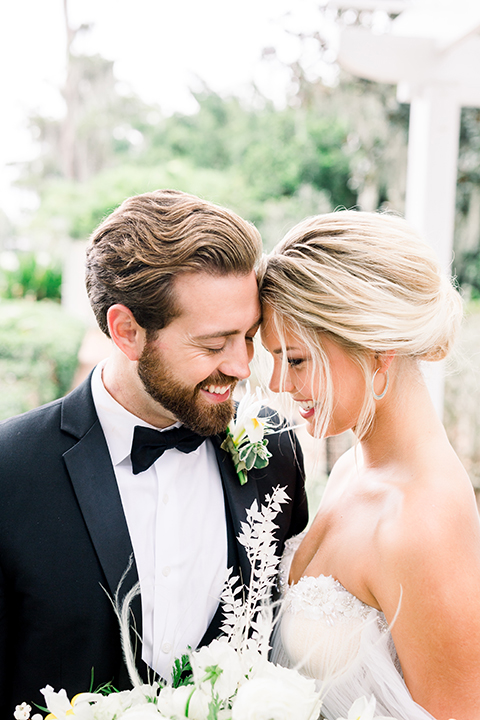  bride in a flowing gown with an off the shoulder detail and the groom in a black tuxedo