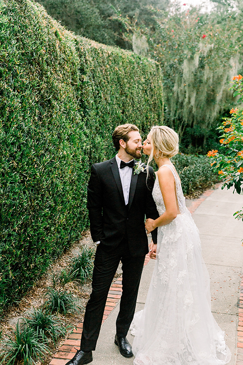  bride in a flowing gown with an off the shoulder detail and the groom in a black tuxedo