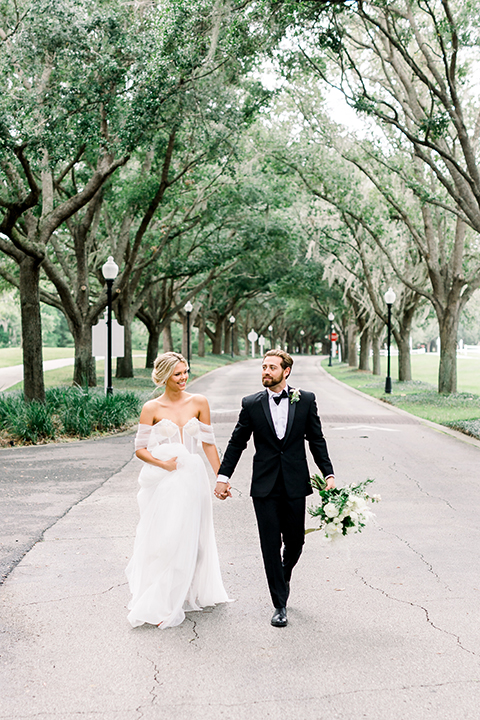  bride in a flowing gown with an off the shoulder detail and the groom in a black tuxedo 