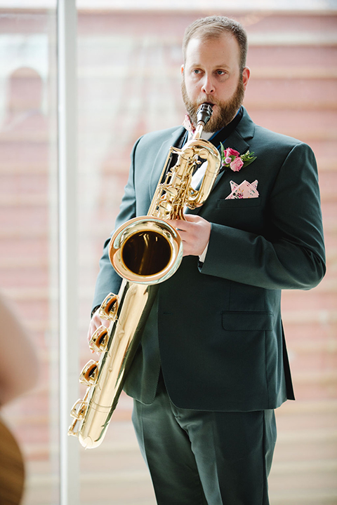  groom in a green suit with a pink floral bow tie and bride in a white a line gown with colorful flowers 