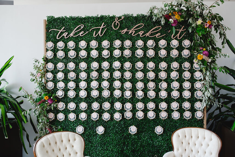  groom in a green suit with a pink floral bow tie and bride in a white a line gown with colorful flowers 