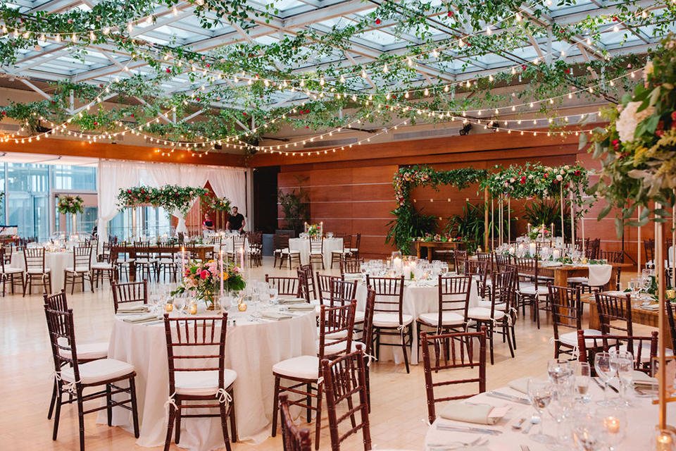  groom in a green suit with a pink floral bow tie and bride in a white a line gown with colorful flowers 