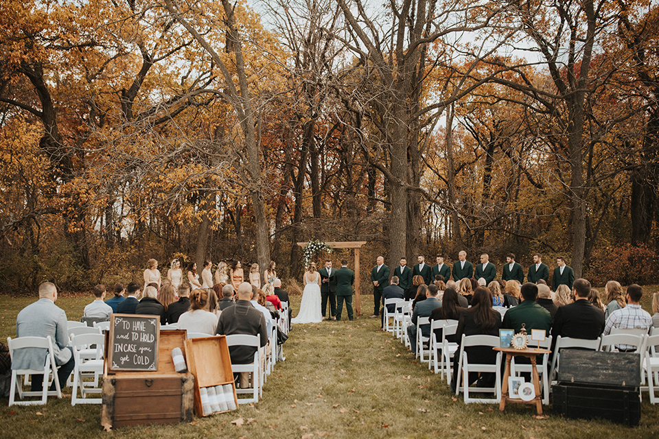  bride in a modern boho gown and the groom and groomsmen in green suits and the bridesmaids in blush gowns 