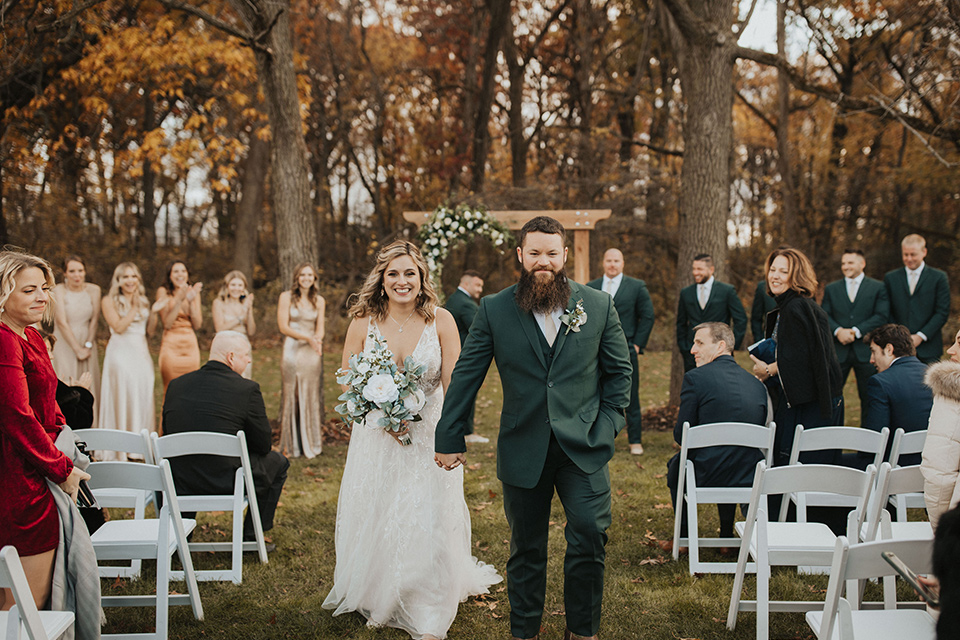  bride in a modern boho gown and the groom and groomsmen in green suits and the bridesmaids in blush gowns 