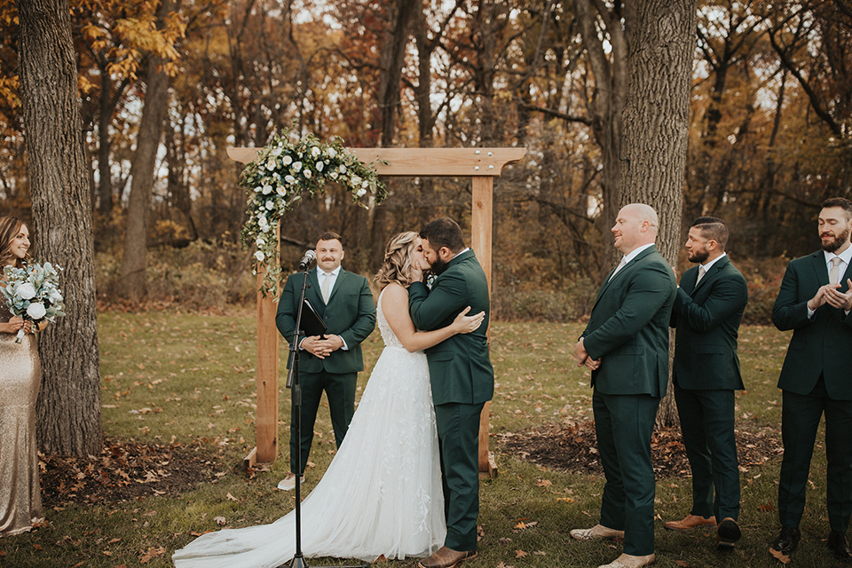  bride in a modern boho gown and the groom and groomsmen in green suits and the bridesmaids in blush gowns 