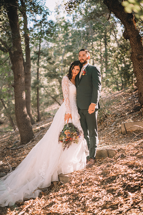  camp wrightwood wedding with the groom in a green suit and floral tie and the bride in a ballgown with lace sleeves 