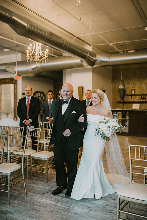  bride in an off the shoulder modern gown and the groom in a charcoal shawl lapel tuxedo 