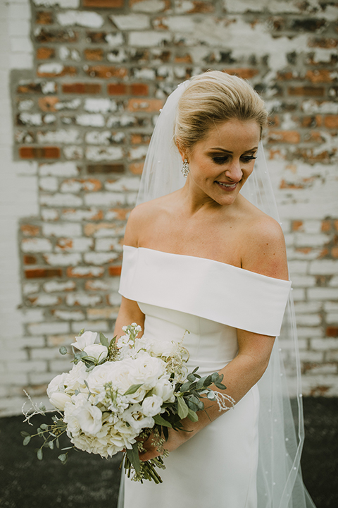  bride in an off the shoulder modern gown and the groom in a charcoal shawl lapel tuxedo 